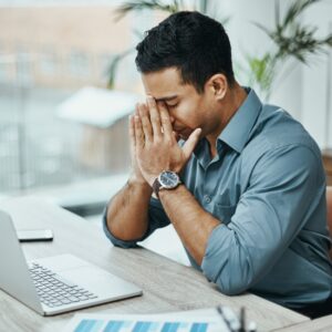 Stressed man sitting at desk in front of laptop 