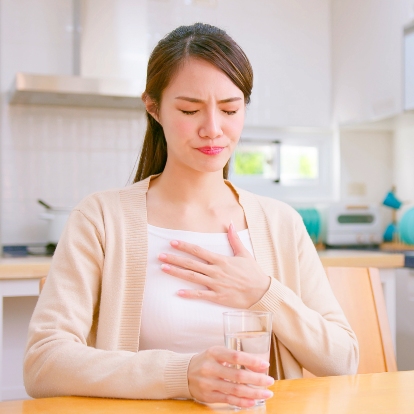 Woman Experiencing Acid Reflux in Kitchen