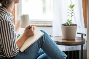 Woman journaling next to window to combat anxiety