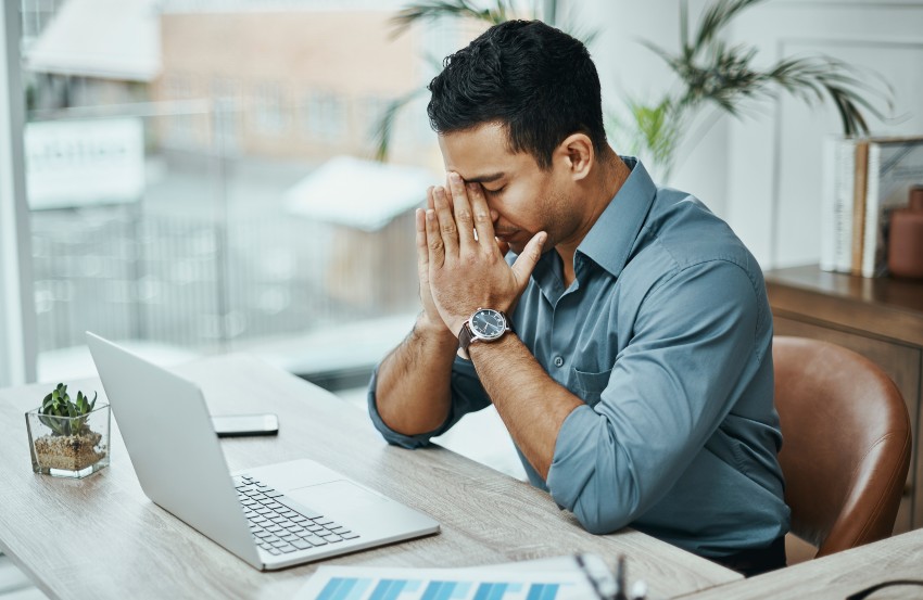 A man with a laptop looking sad symbolizing stress and anxiety issues in San Diego, CA