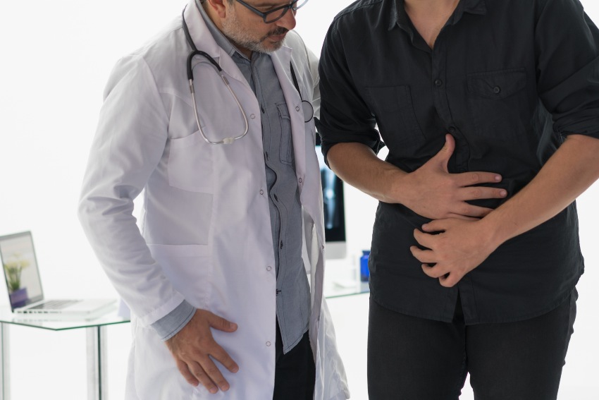 A doctor examines a man's abdomen discussing Ulcerative Colitis vs. Crohn’s Disease in San Diego, CA