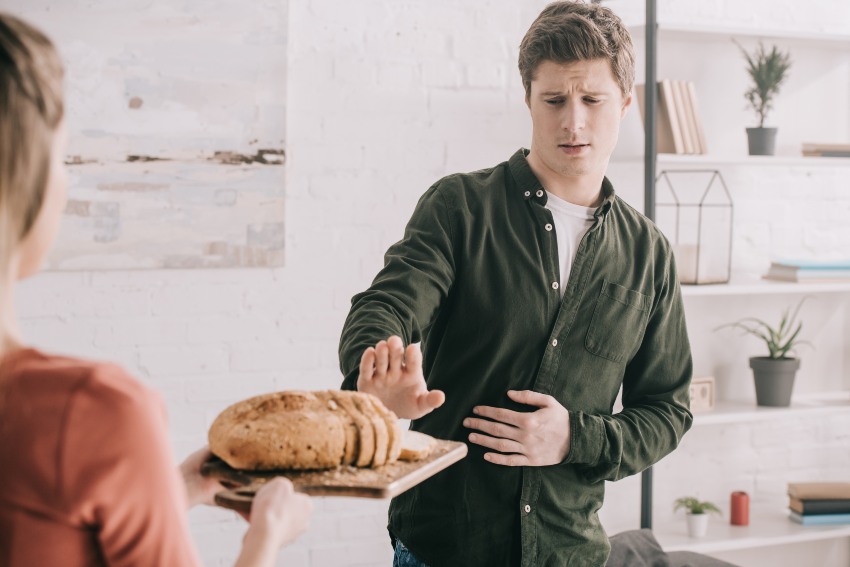 A women offers bread to a man emphasizing eating choices for people with celiac disease in San Diego