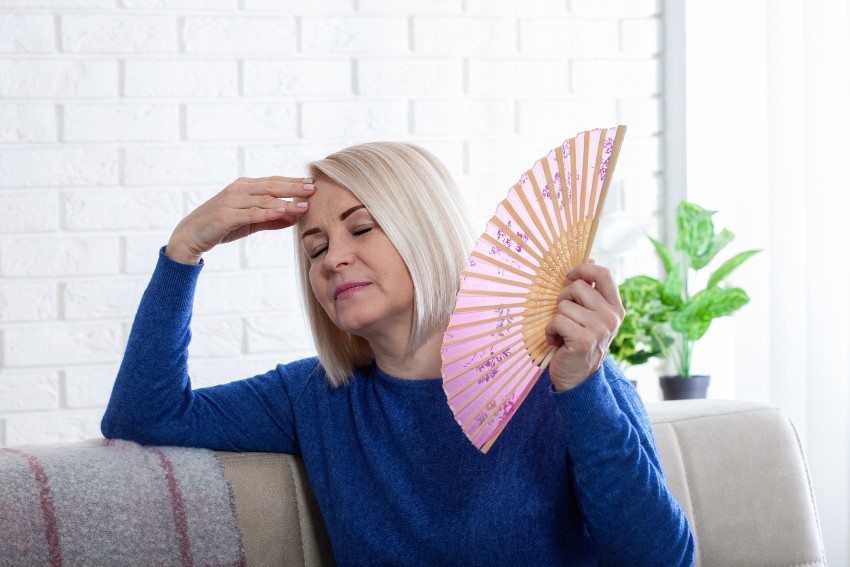 A woman holding a fan highlighting strategies for managing menopausal hot flashes in San Diego, CA