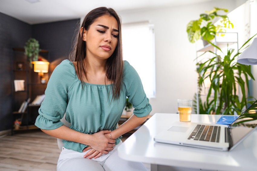 A woman visibly distressed holding her stomach in pain representing abdominal pain in San Diego, CA