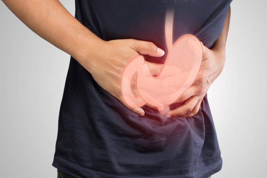 A man holds his abdomen depicting discomfort related to GERD triggers & heartburn in San Diego, CA
