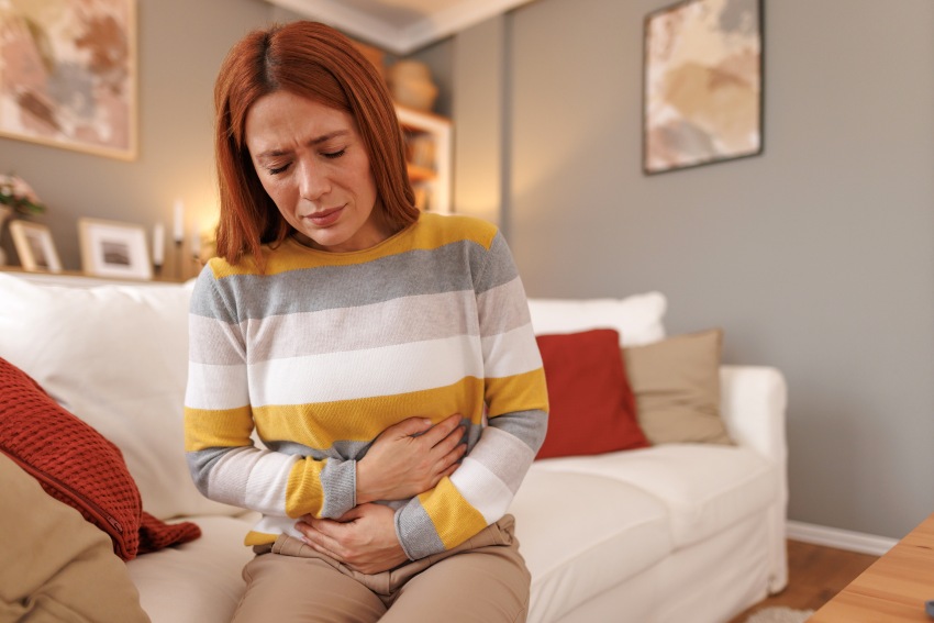 A woman grimacing in discomfort illustrating bloating issues in San Diego, CA